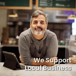 Middle aged man leaning on counter with an iPad set up with text "We support Local Business" 